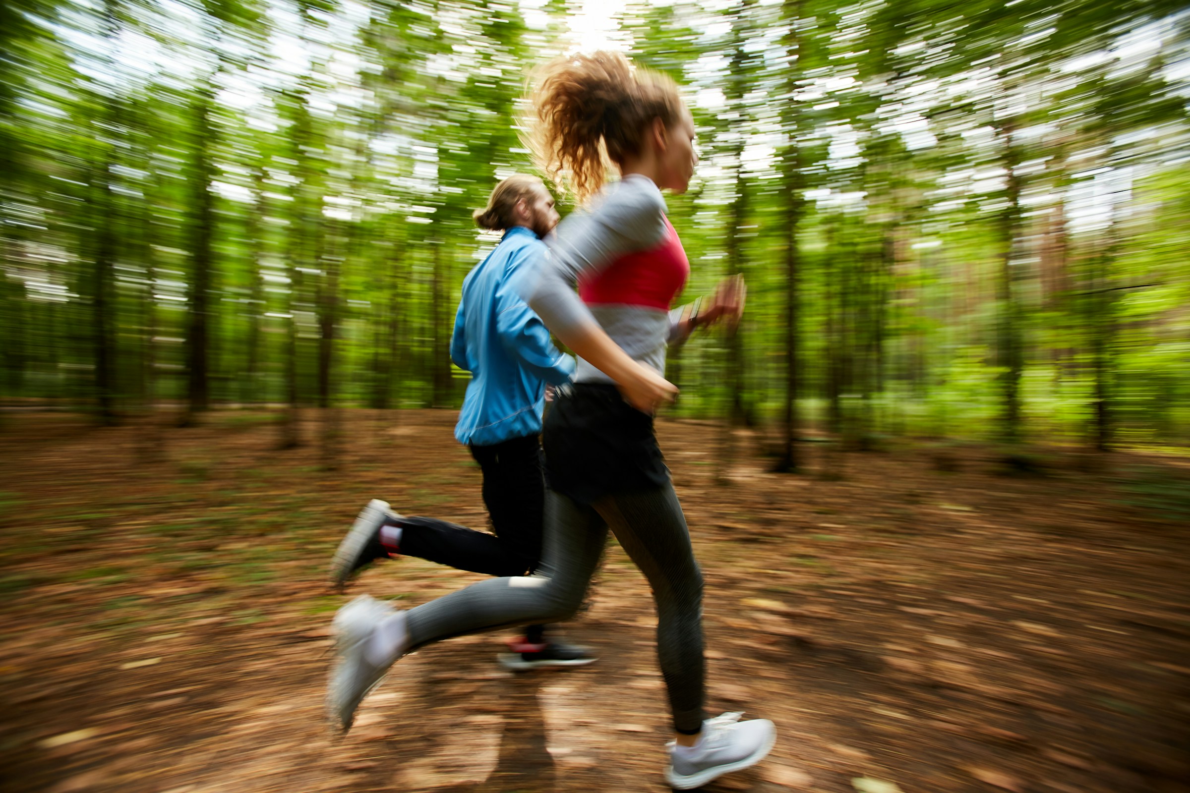 Two people running along a woodland trail.